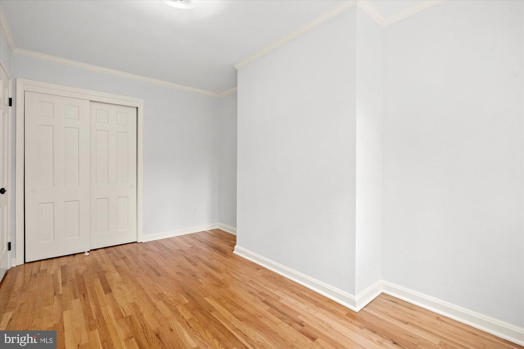 Empty room with hardwood floors and white paneled closet doors.