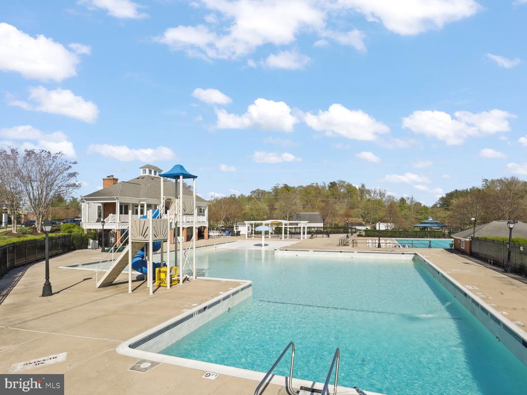 Community swimming pool with a shallow area and playground slide beside the deck.