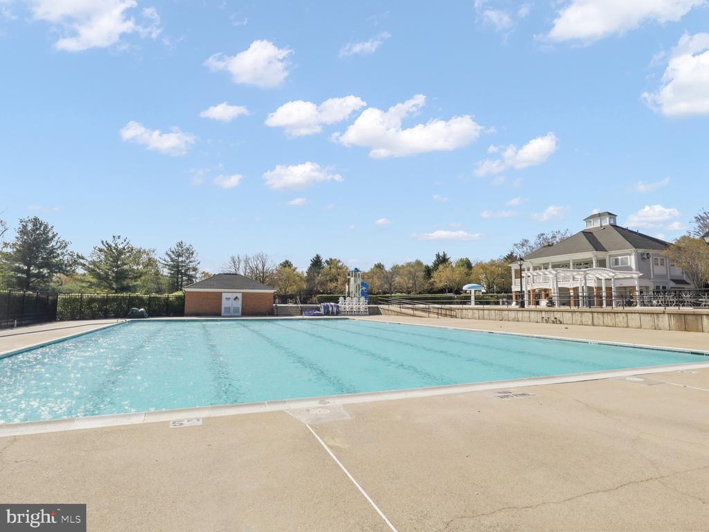 Community swimming pool beside a clubhouse and water-play structure.