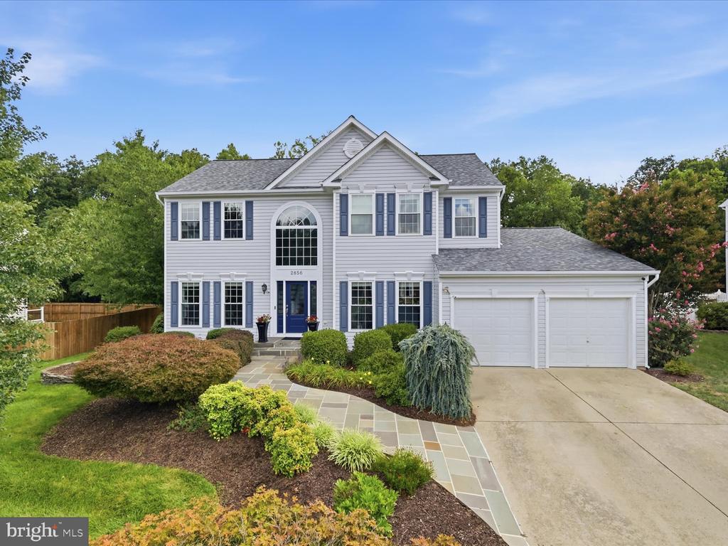 Two-story home with blue shutters, an arched entry, and an attached two-car garage.