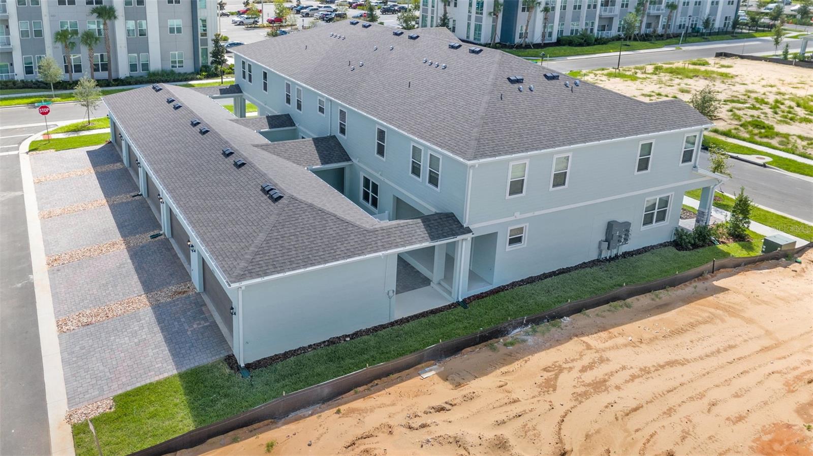 Aerial view of a two-story residential building with multiple garage bays and paved parking areas.