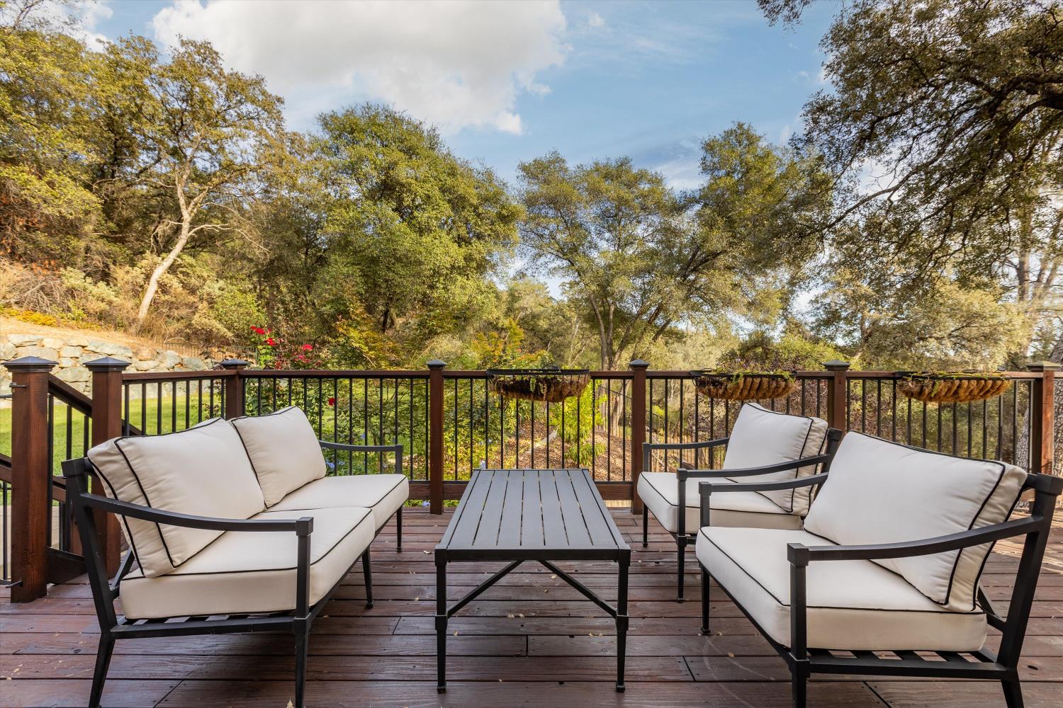 Wooden deck with cream-cushioned seating overlooking autumn trees.
