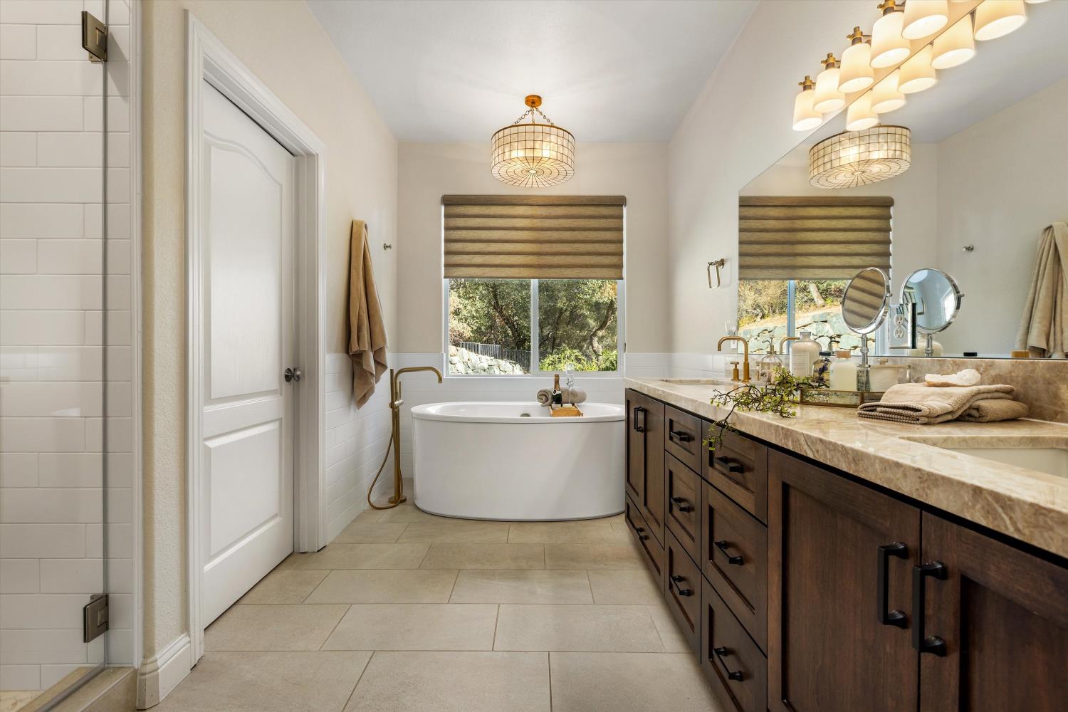 Bathroom with a freestanding soaking tub, window, and long dark wood double vanity.