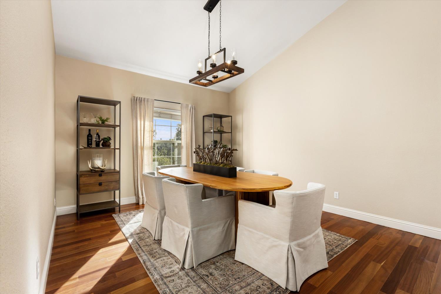 Staged dining room with an oval wood table, upholstered chairs, and a modern pendant light.