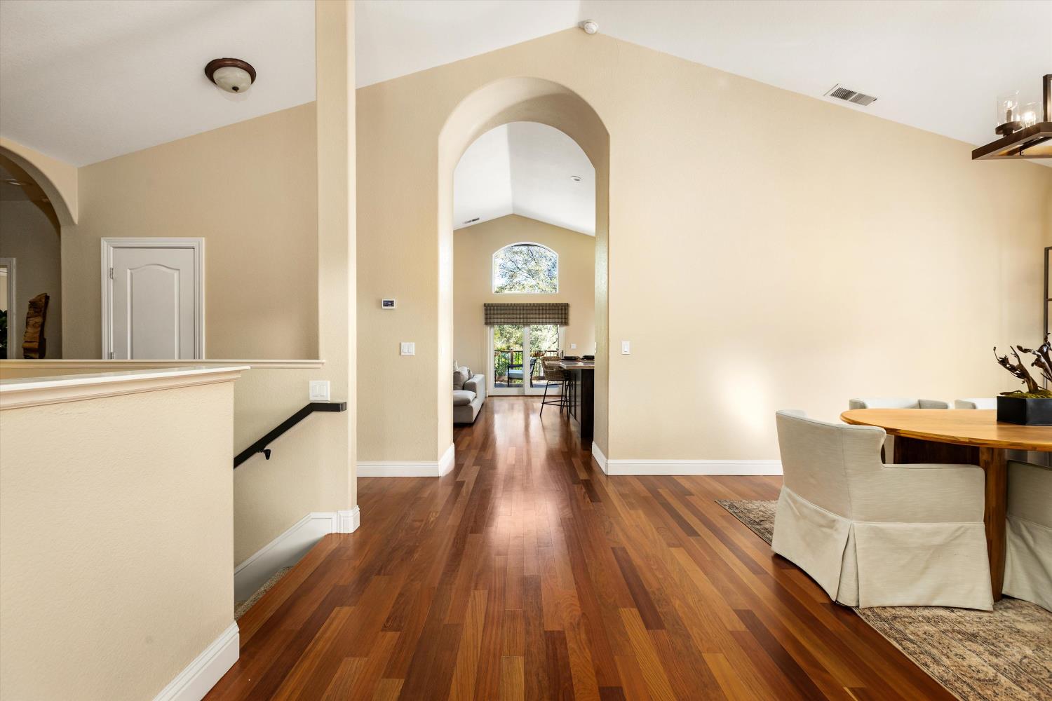 Home interior with an arched hallway, hardwood floors, and a dining area.
