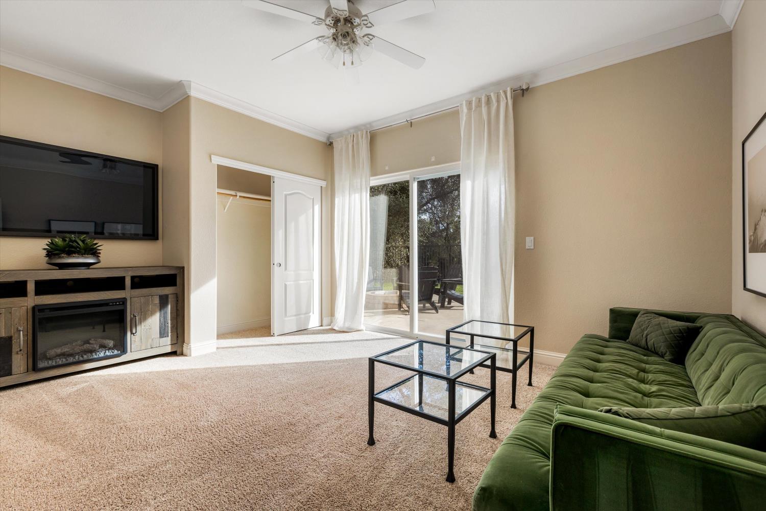 Living room with a green tufted sofa, glass coffee tables, and sliding doors to a patio.