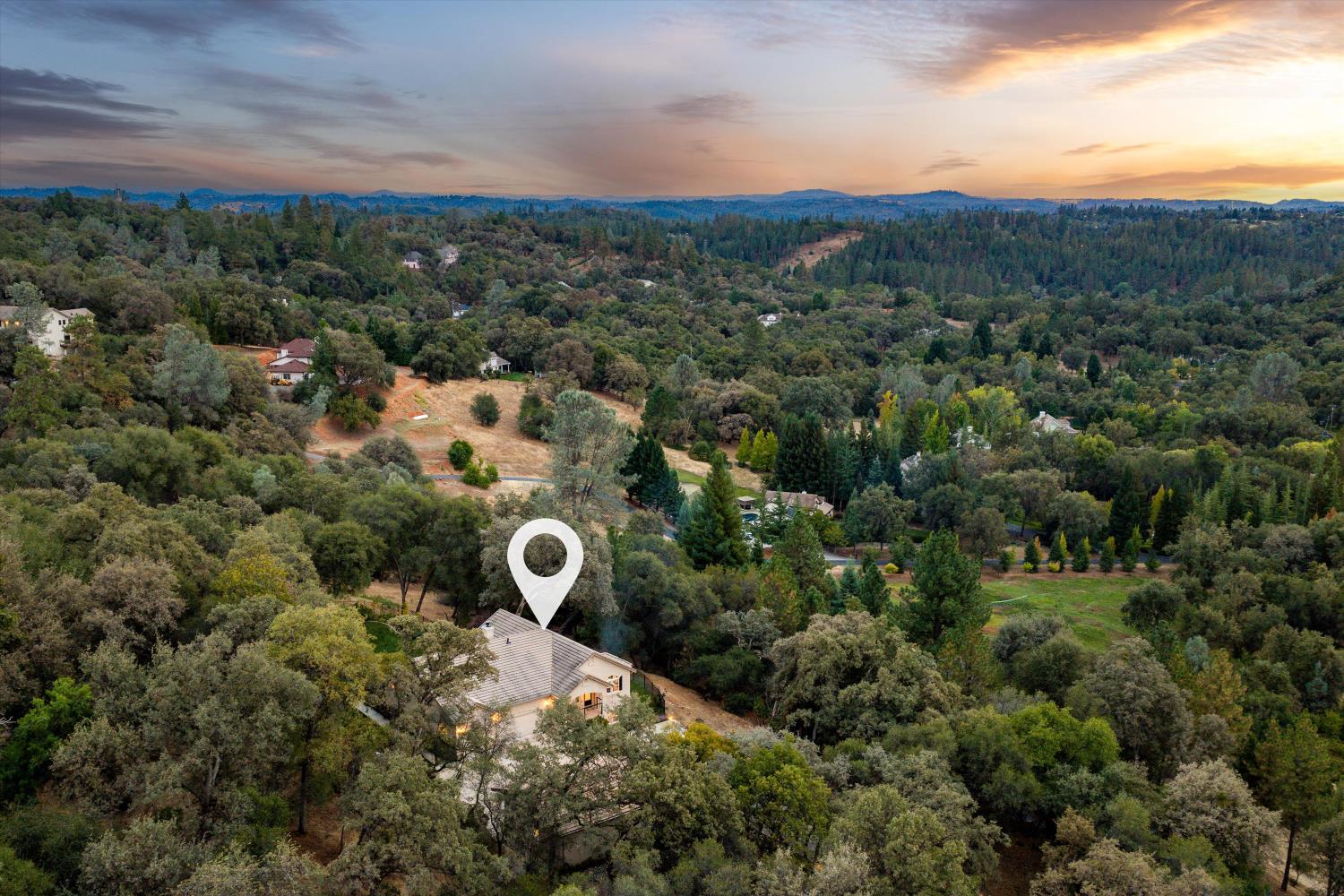 Aerial view of 11120 Shadow Court amid wooded acreage at sunset.