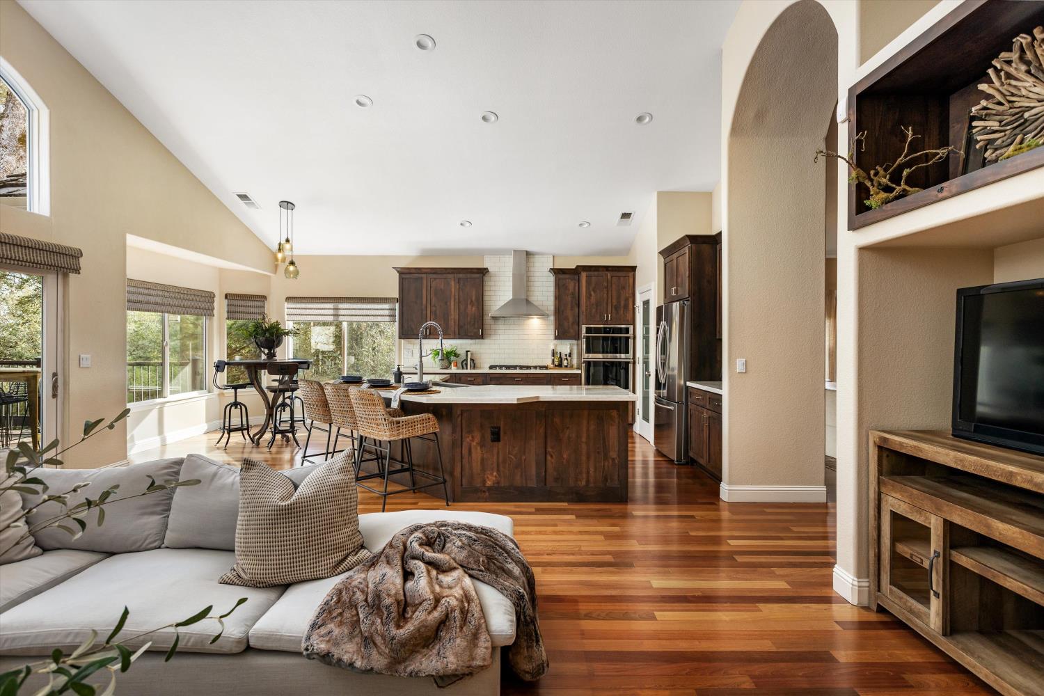 Open-plan kitchen with dark wood cabinetry, a large island, hardwood floors, and an adjoining living area.