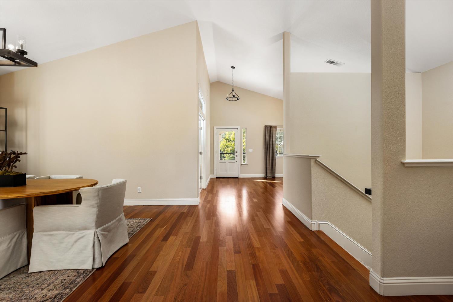 Entry hall with hardwood floors, a high ceiling, front door, and dining area