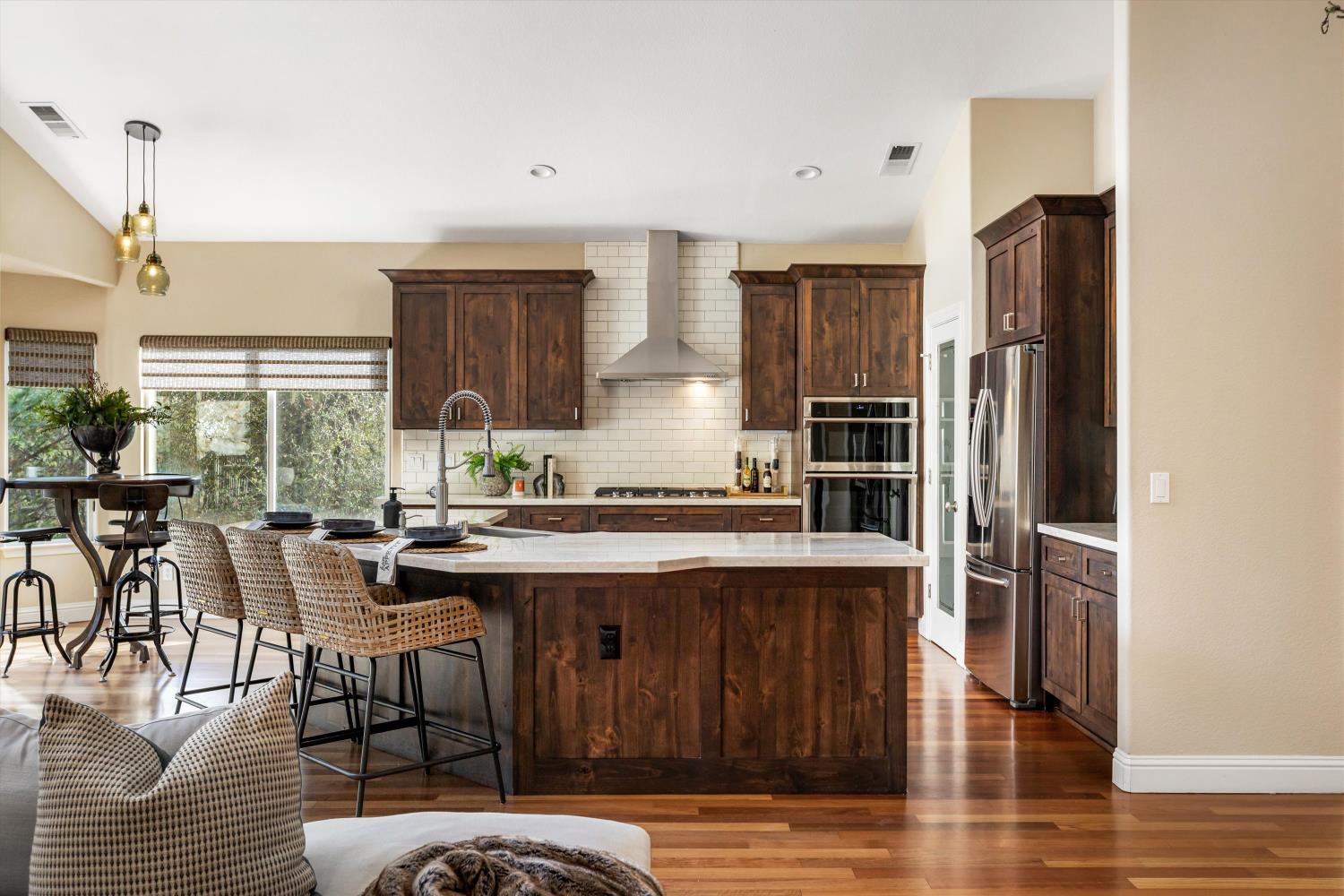 Kitchen with a large island, dark wood cabinets, stainless appliances, and a bright dining nook.