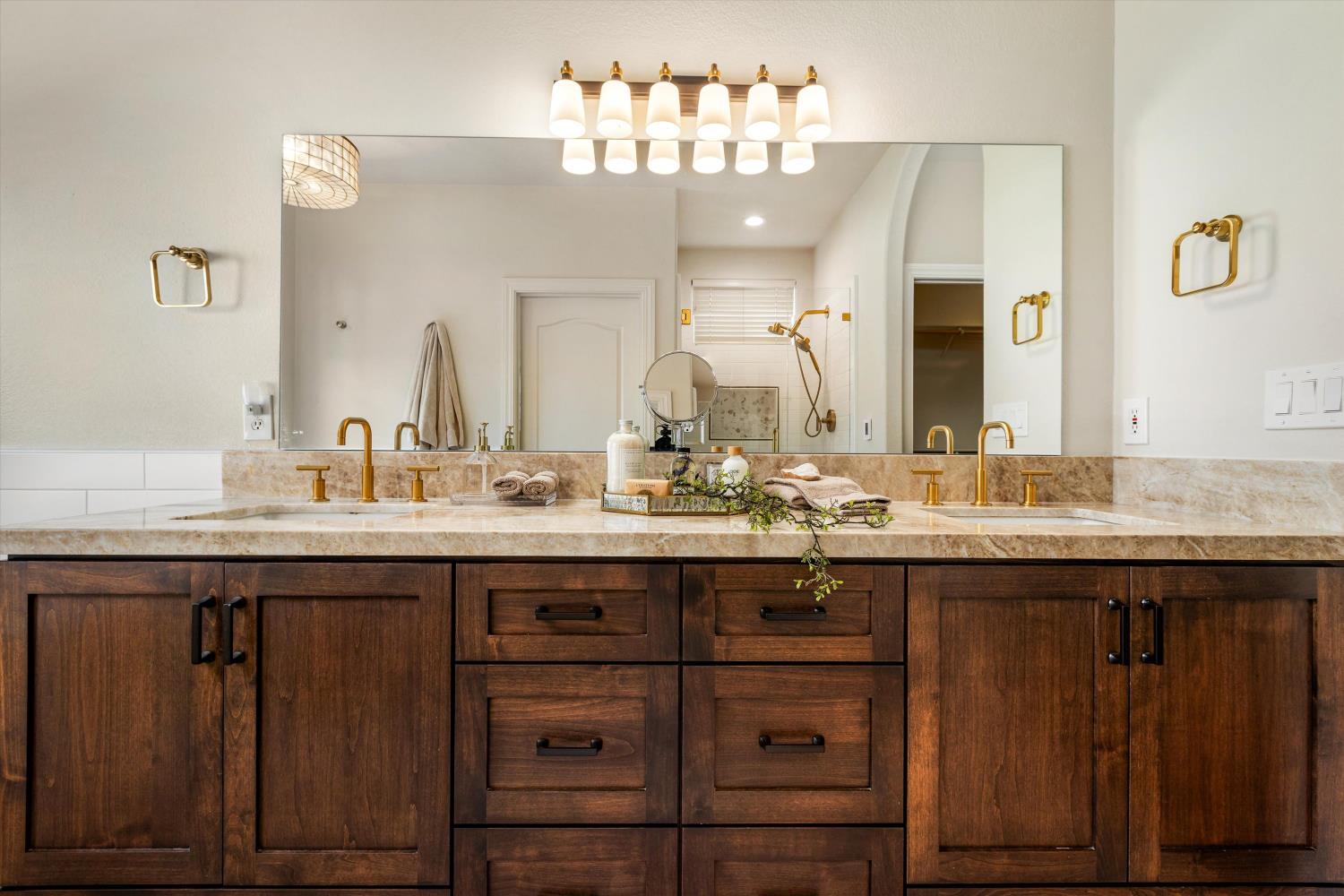 Bathroom vanity with double sinks, brass fixtures, and dark wood cabinetry.