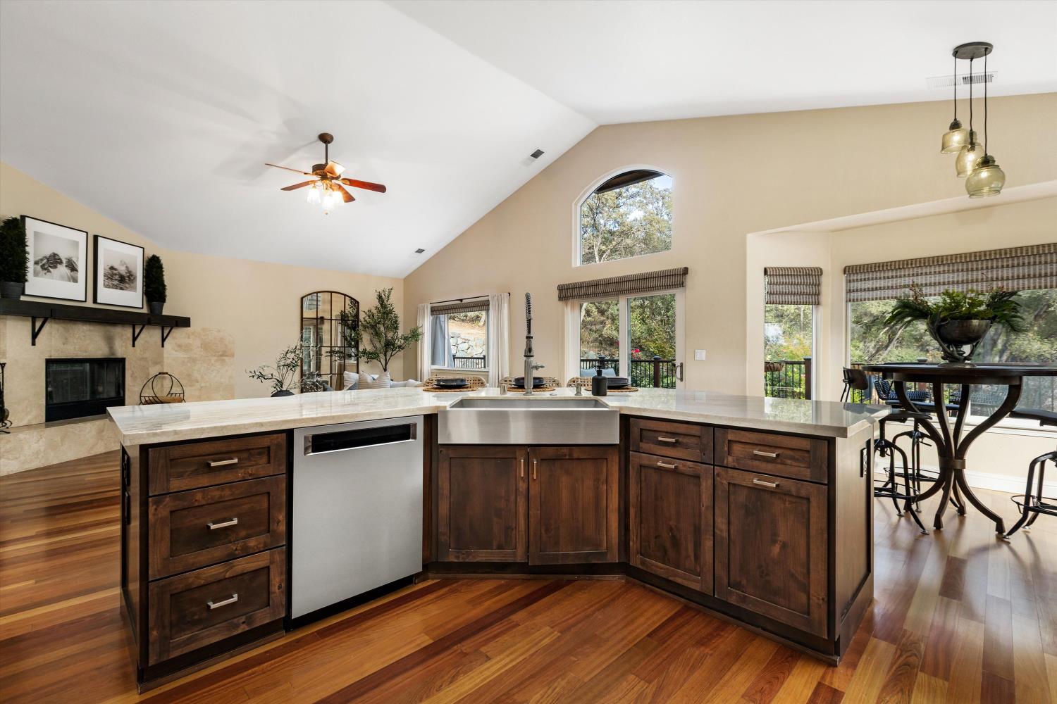 Kitchen with a large dark-wood island, farmhouse sink, stainless dishwasher, and vaulted ceiling.