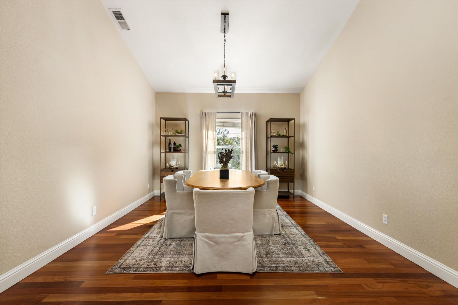 Dining room with a round wooden table, upholstered chairs, and dark hardwood floors.