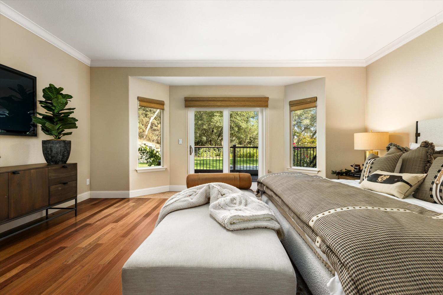 Furnished bedroom with warm wood floors and a sliding glass door overlooking the garden.