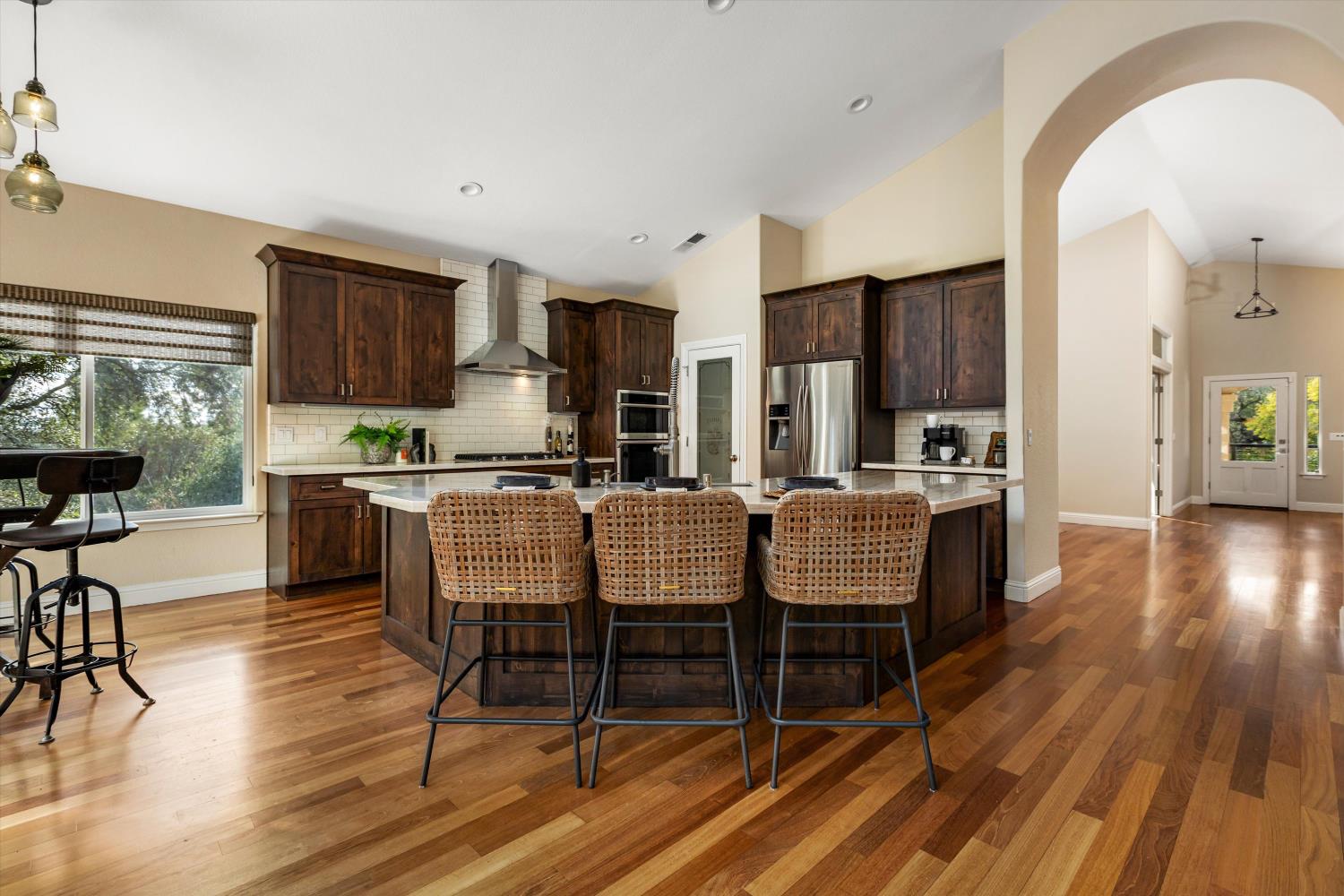 Kitchen with dark wood cabinets, stainless appliances, and a large island with woven stools.