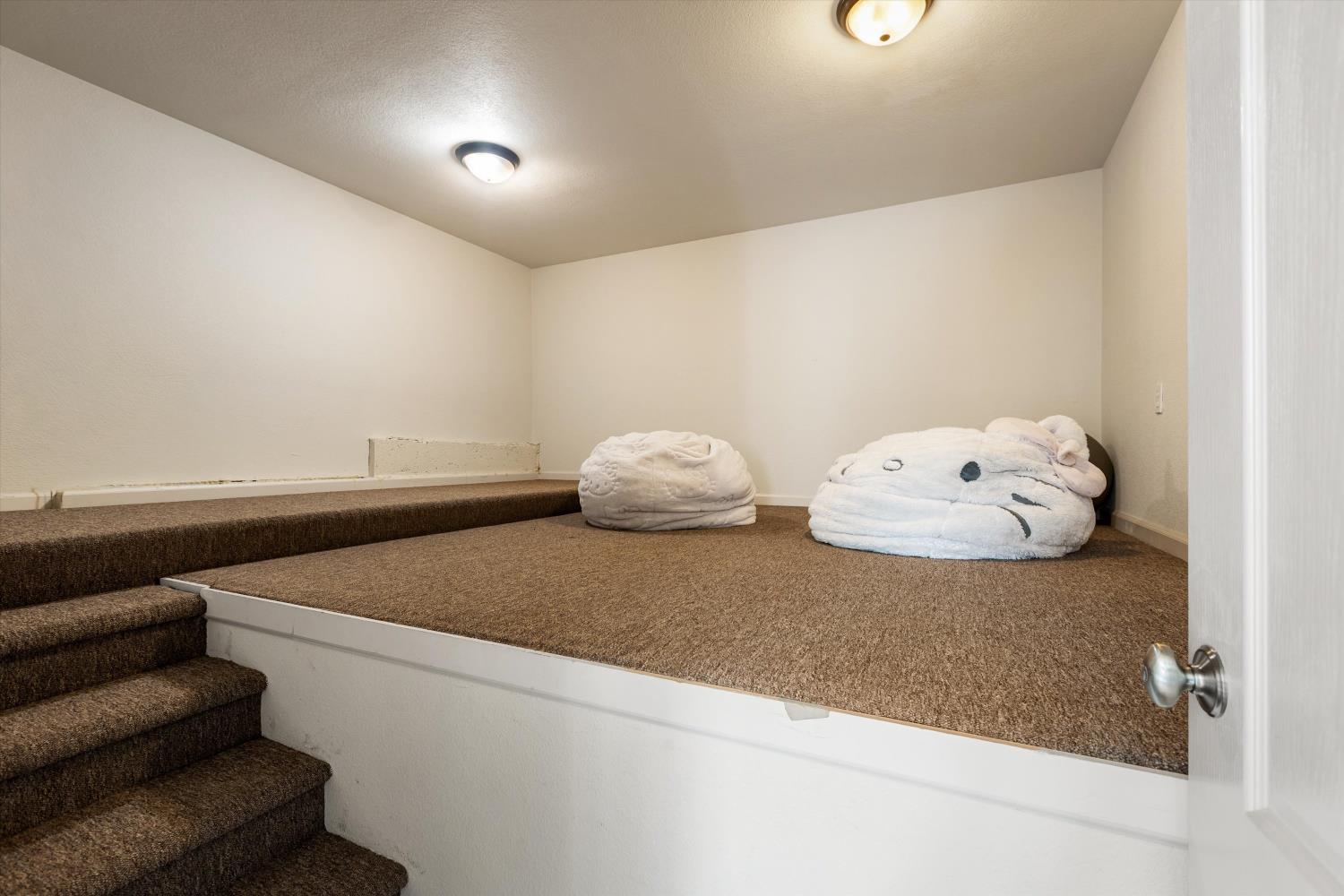 Carpeted raised nook with steps and two oversized plush animal cushions.