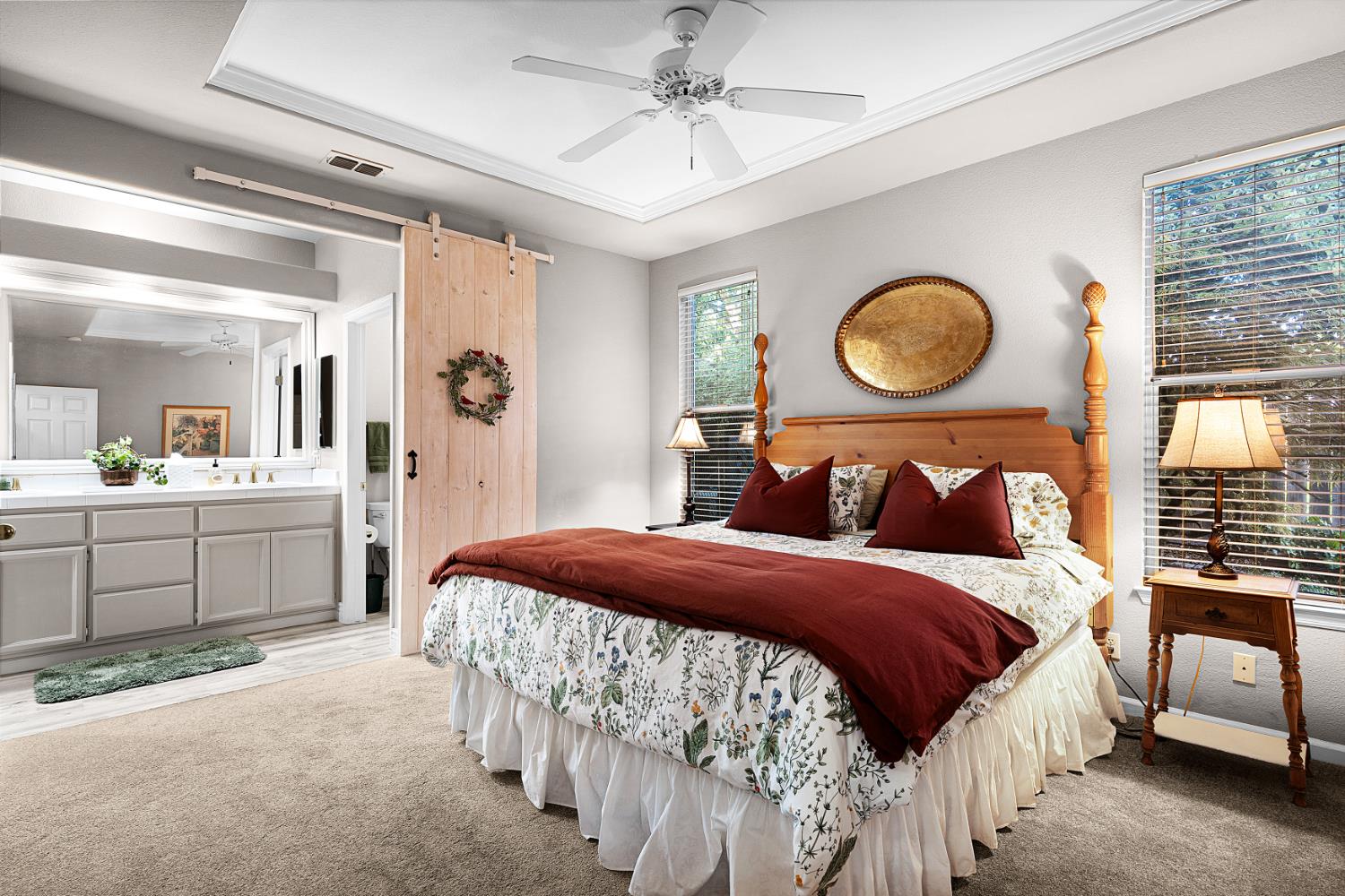 Bedroom with a wooden four-poster bed, floral bedding, burgundy accents, and a sliding barn door.