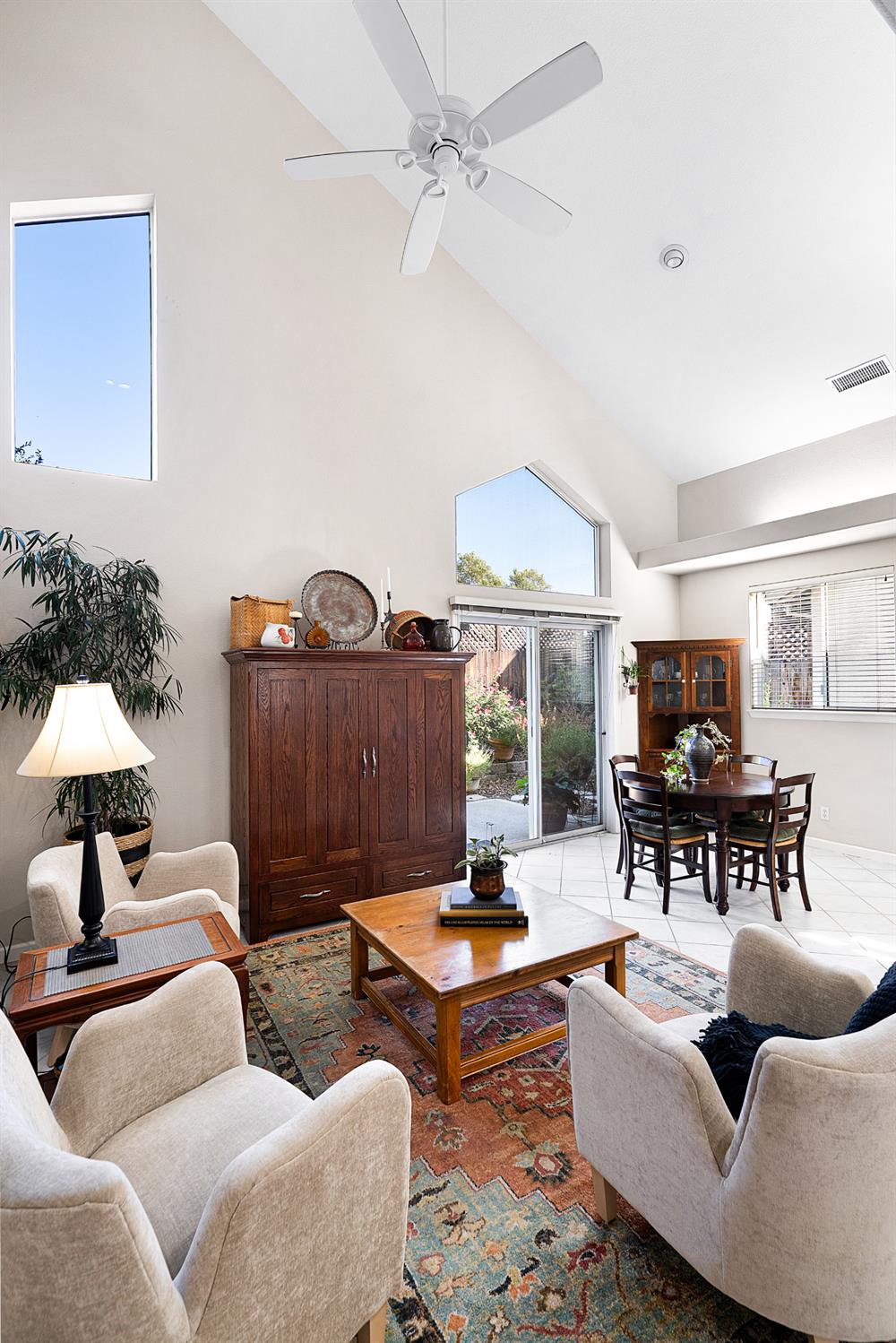 Vaulted living room with a ceiling fan, garden-facing glass doors, and an adjoining dining area.