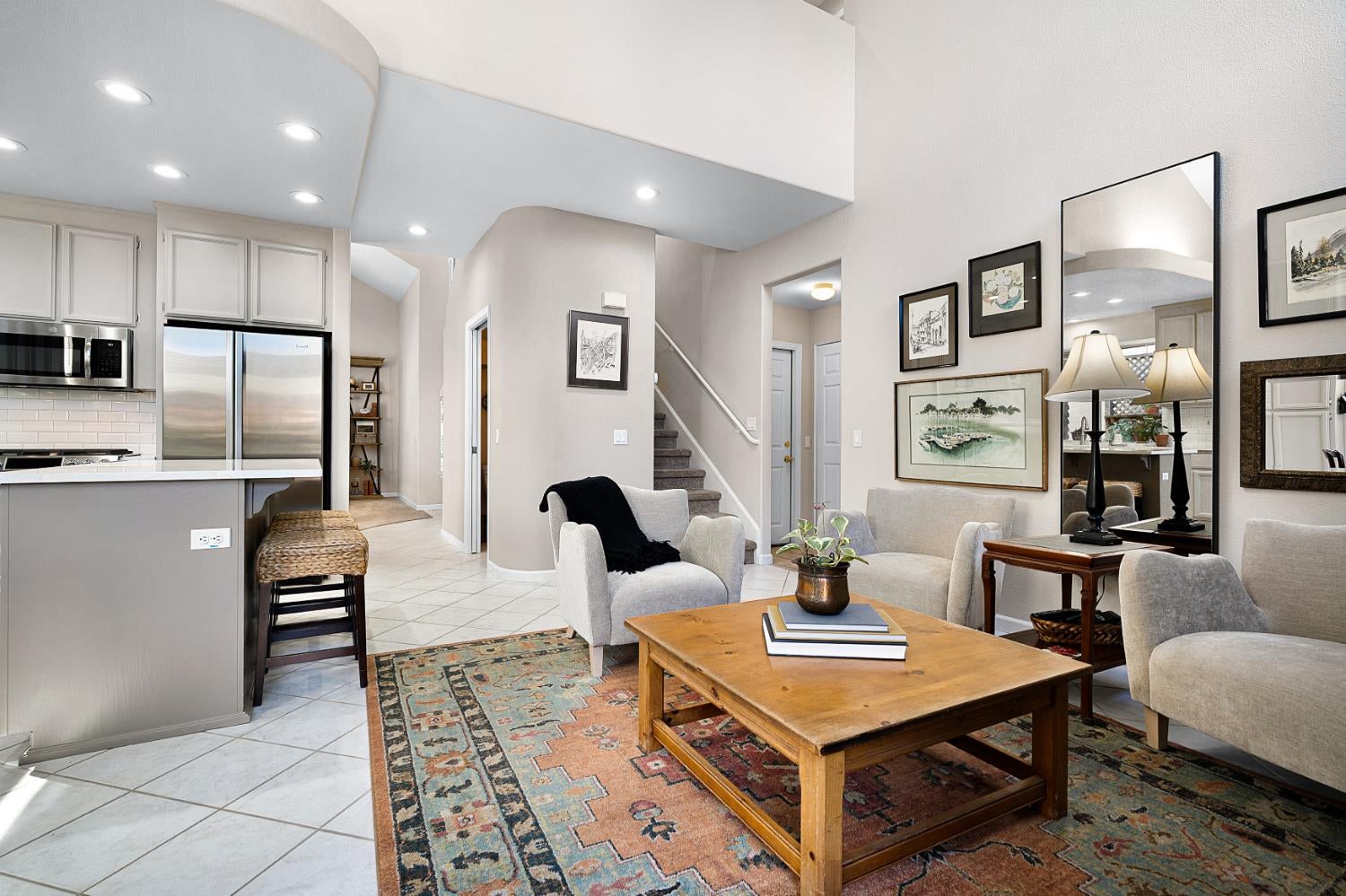 Living room with a patterned rug, wooden coffee table, and open kitchen.