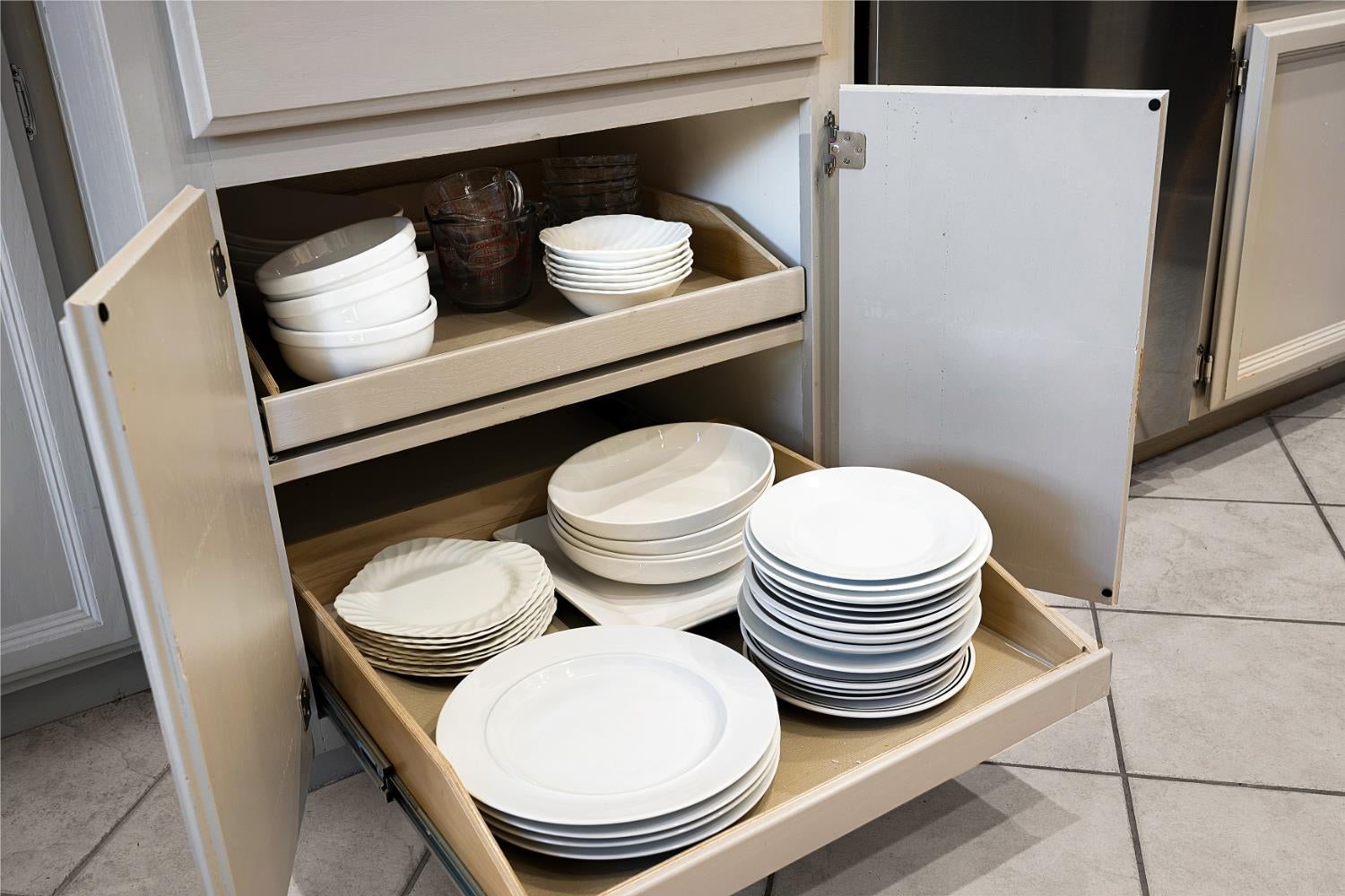 Kitchen pullout drawers stocked with plates, bowls, and glassware