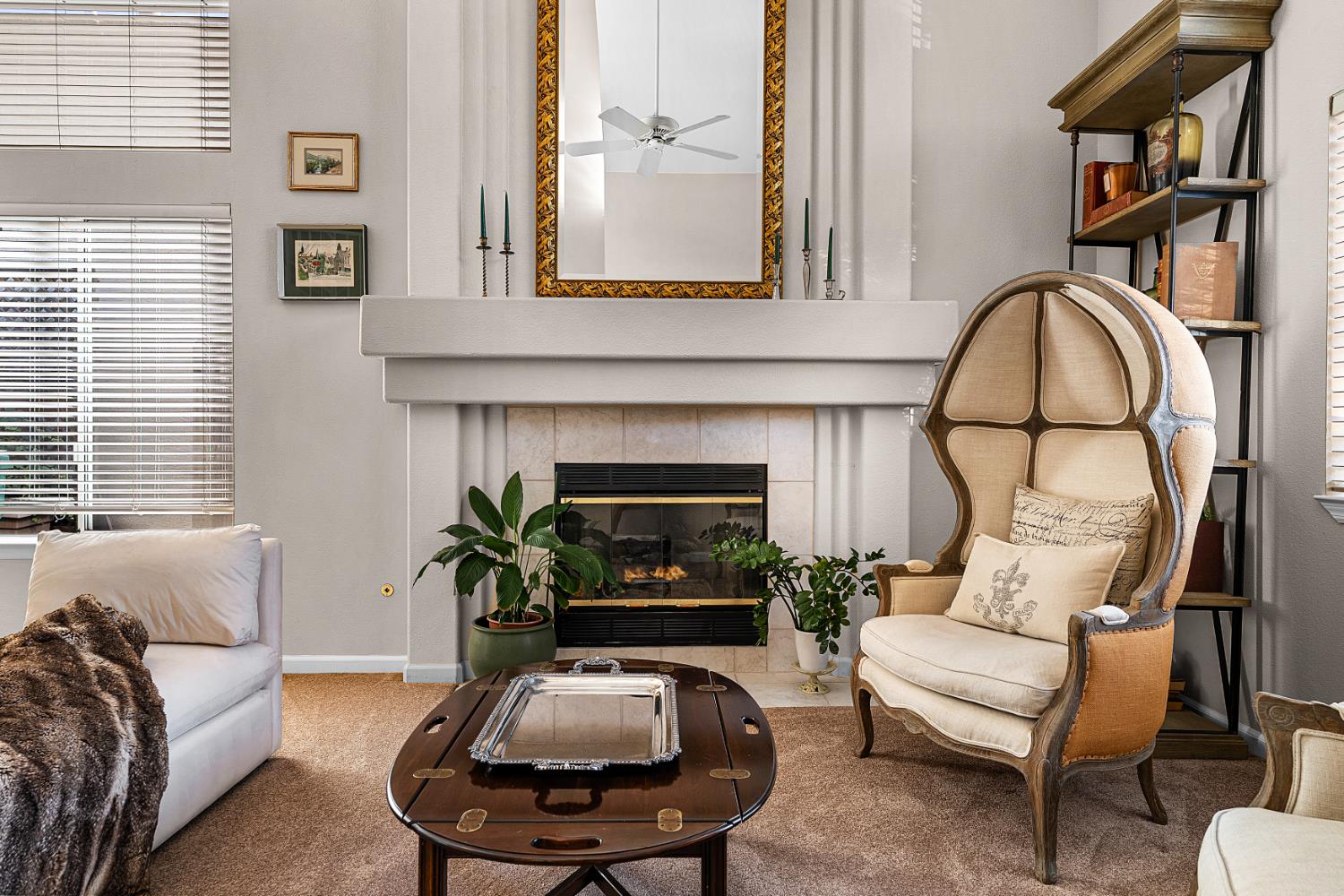 Living room with a tiled fireplace, ornate mirror, and sculptural upholstered armchair.