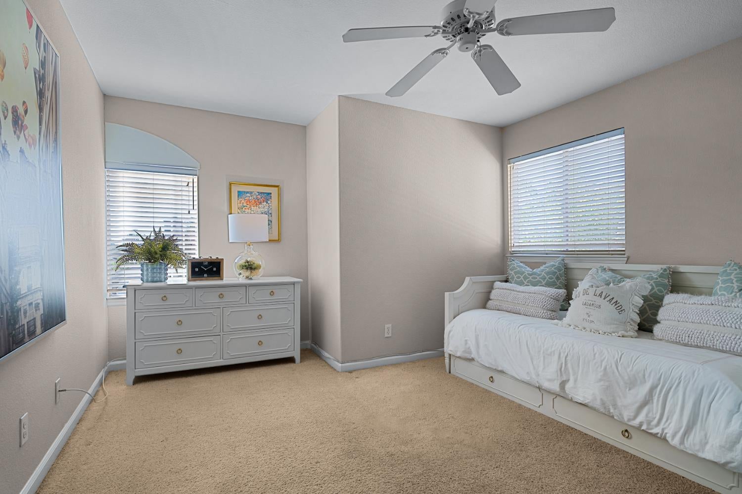 Bedroom with a white daybed, pale aqua pillows, beige carpet, and a ceiling fan.