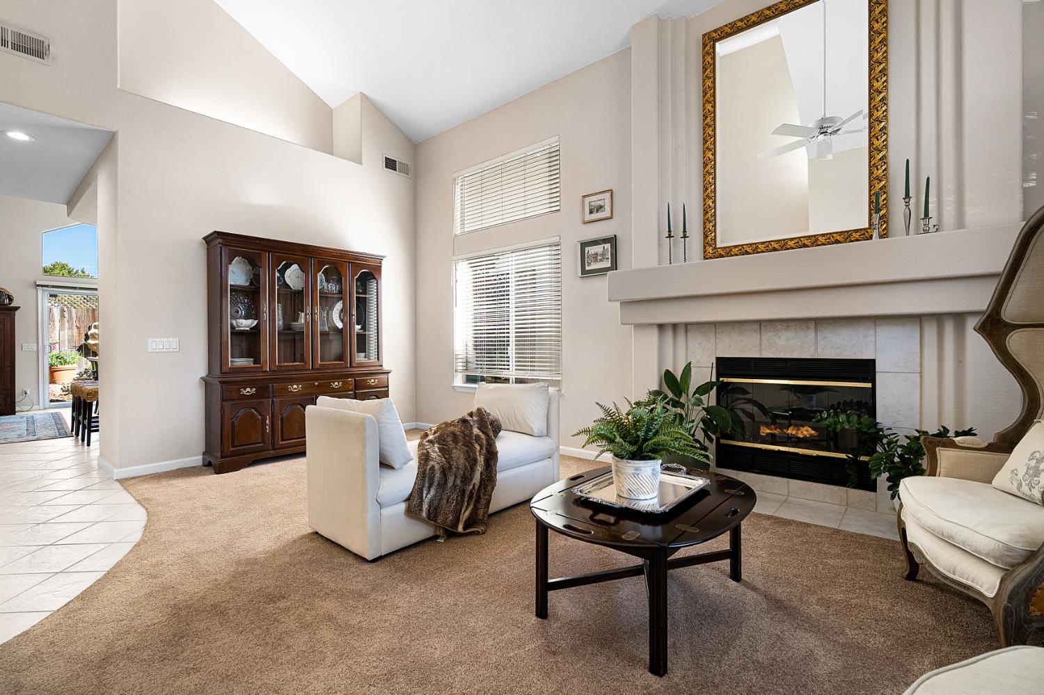Furnished living room with a vaulted ceiling, tall windows, and a tiled fireplace.