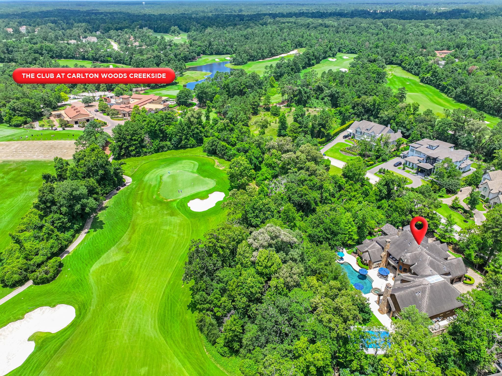 Aerial view of a home with a pool beside the golf course at Carlton Woods Creekside.