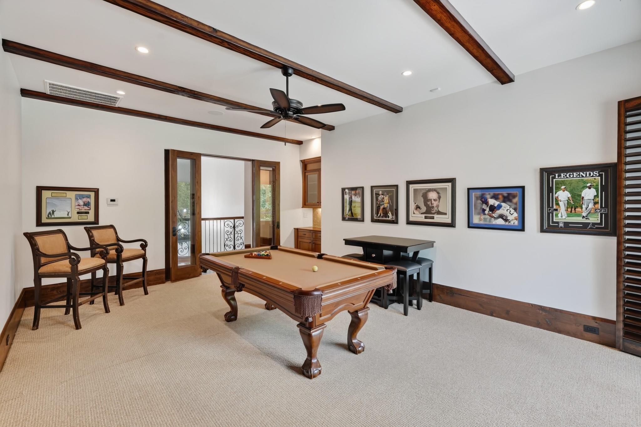 Game room with a wooden pool table, upholstered chairs, and framed sports memorabilia.