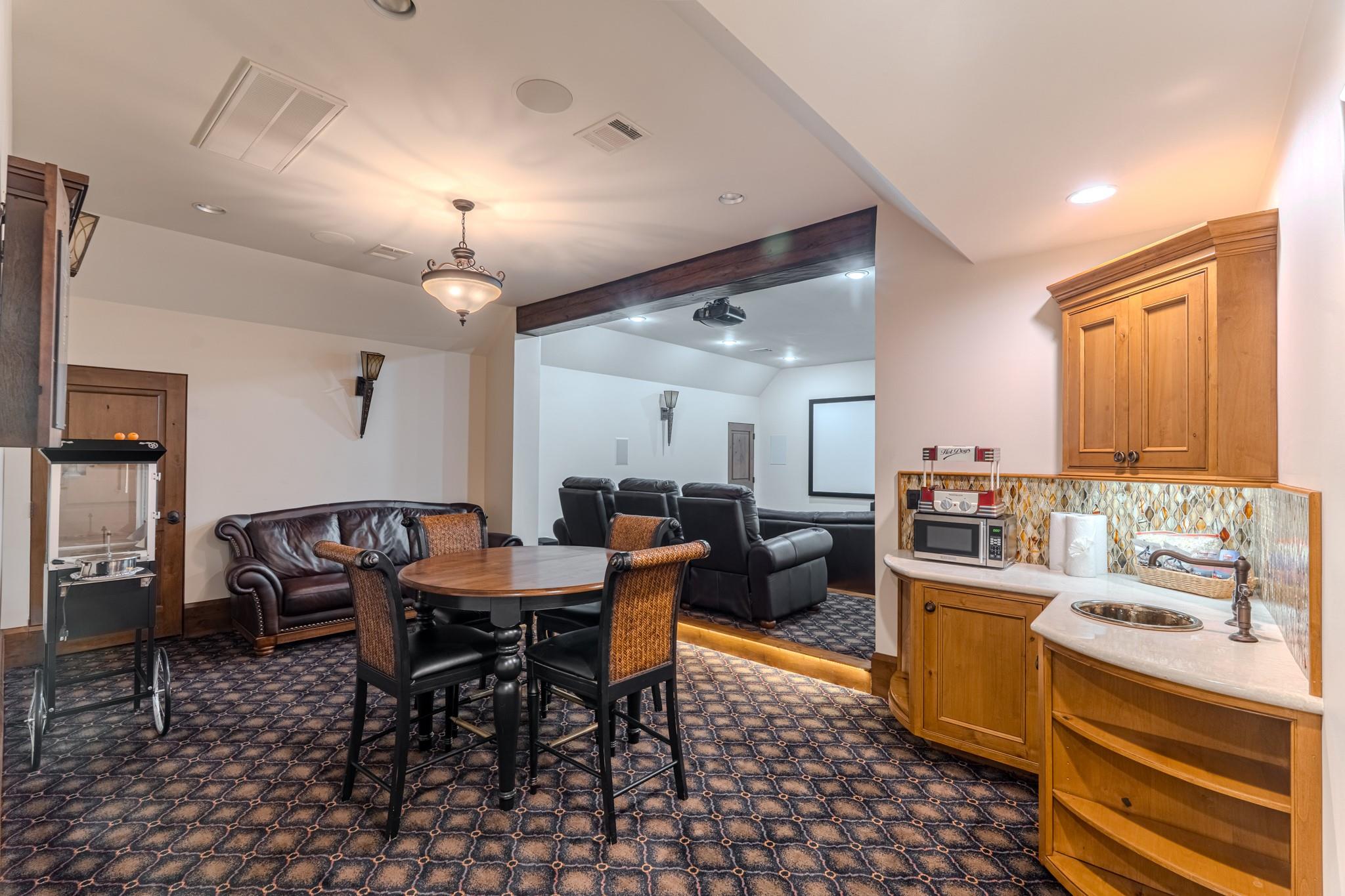 Furnished media room with theater seating, a dining table, kitchenette, and hot dog cart.