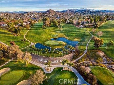 Aerial view of a golf course with ponds, winding paths, and surrounding hills.