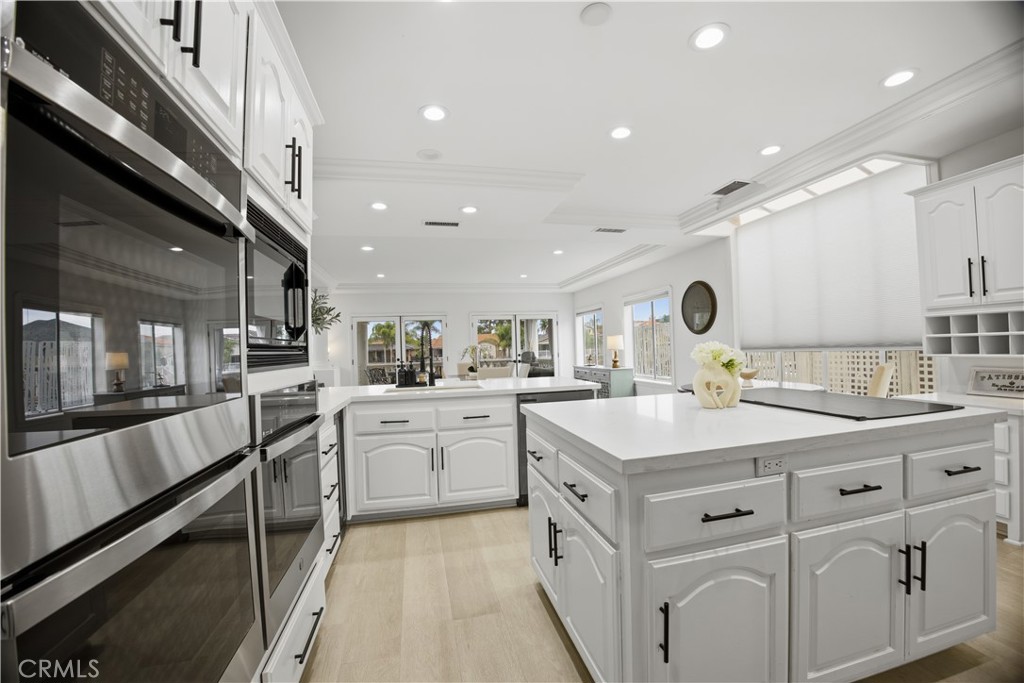 Bright white kitchen with stainless steel ovens, two large islands, and expansive windows.