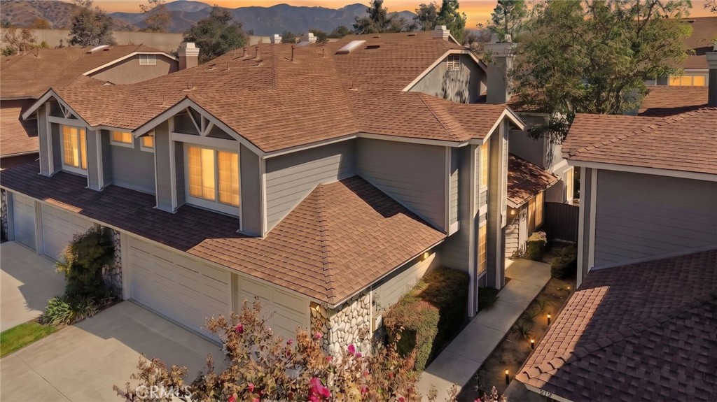 Aerial view of a two-story home with attached garages and tiled roofs at sunset.