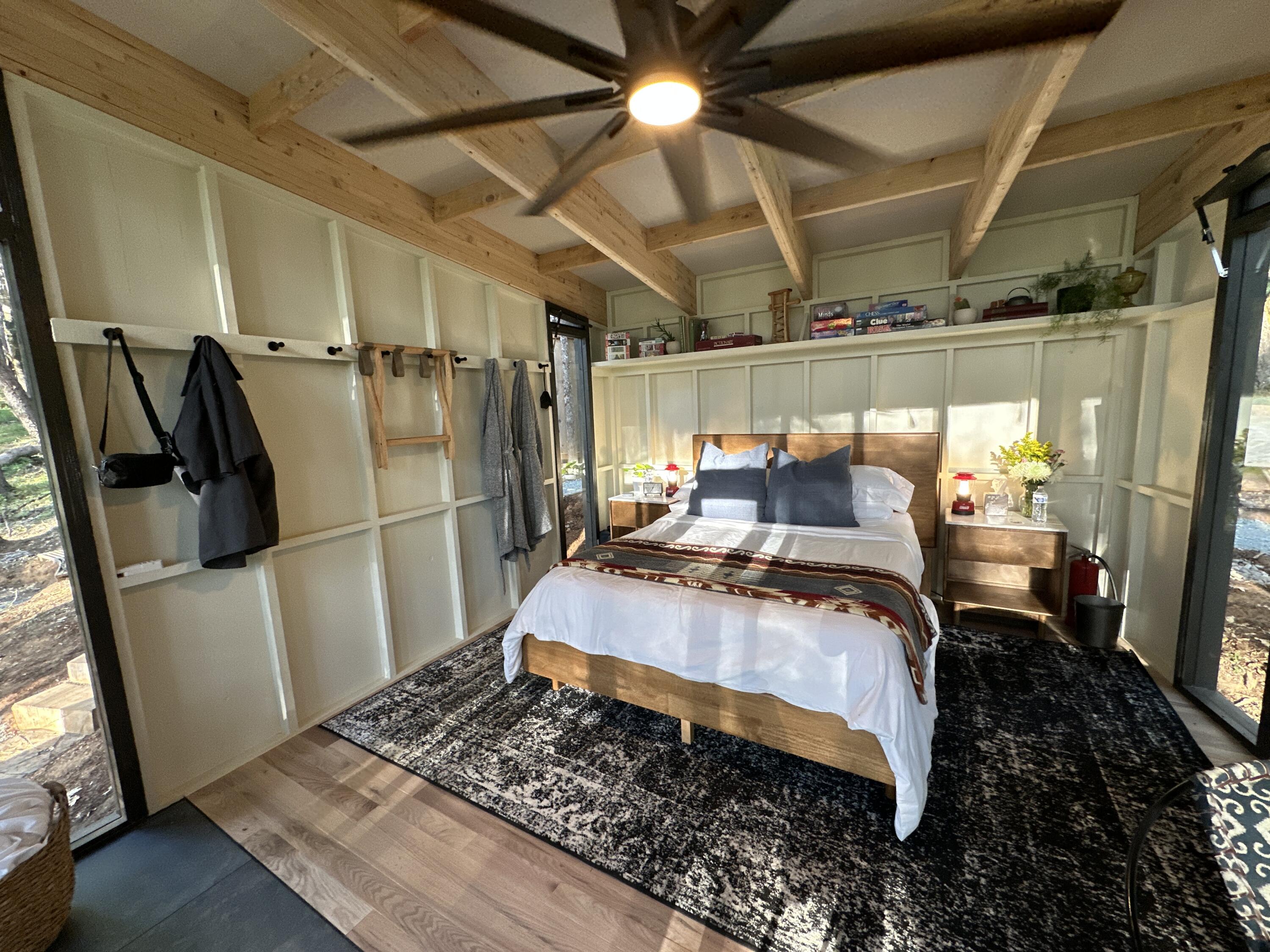 Bedroom with exposed timber ceiling beams, a wooden bed, and glass doors opening to the outdoors.