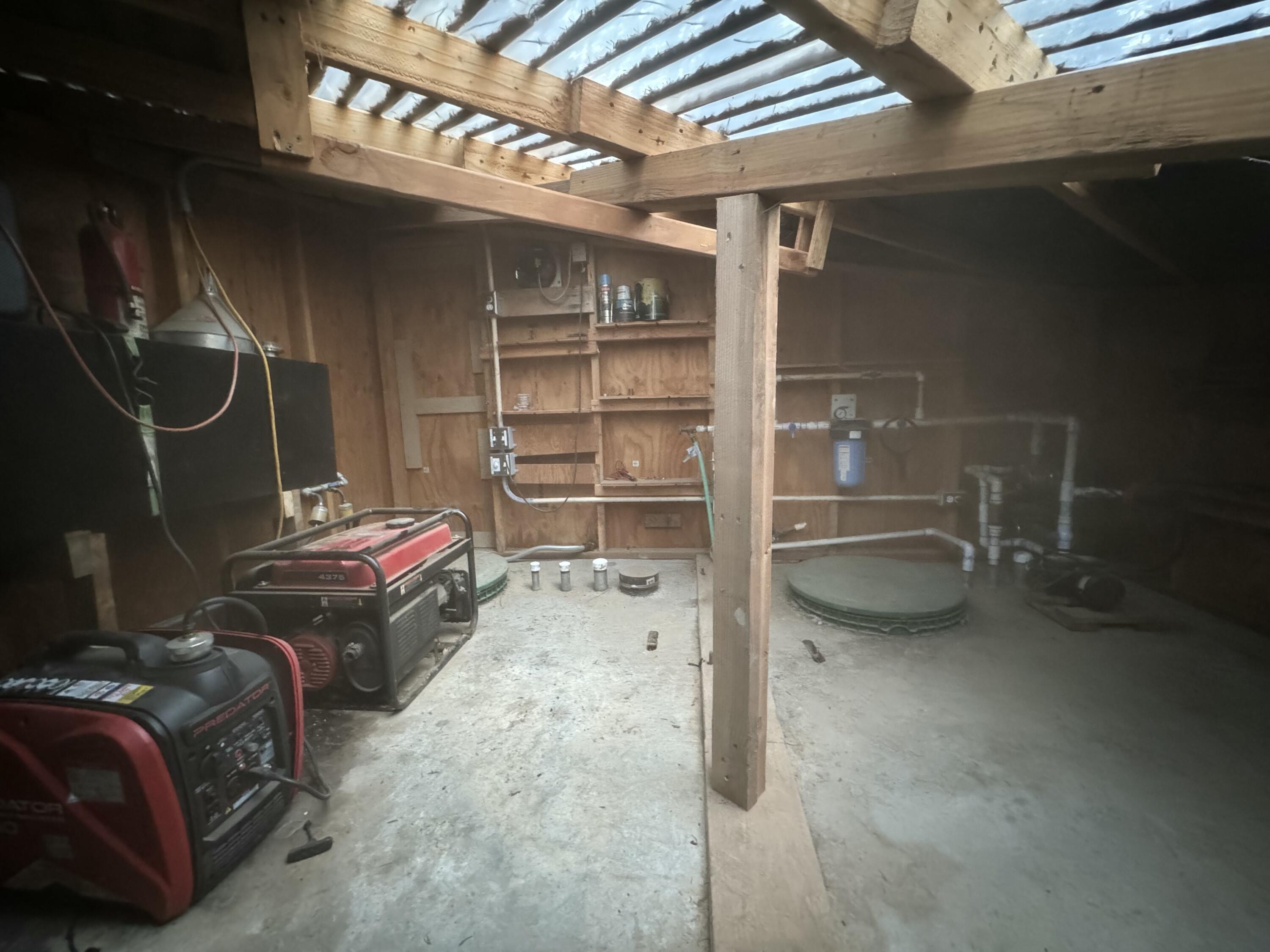 Utility room with two portable generators, exposed plumbing, and circular access covers beneath a translucent roof.
