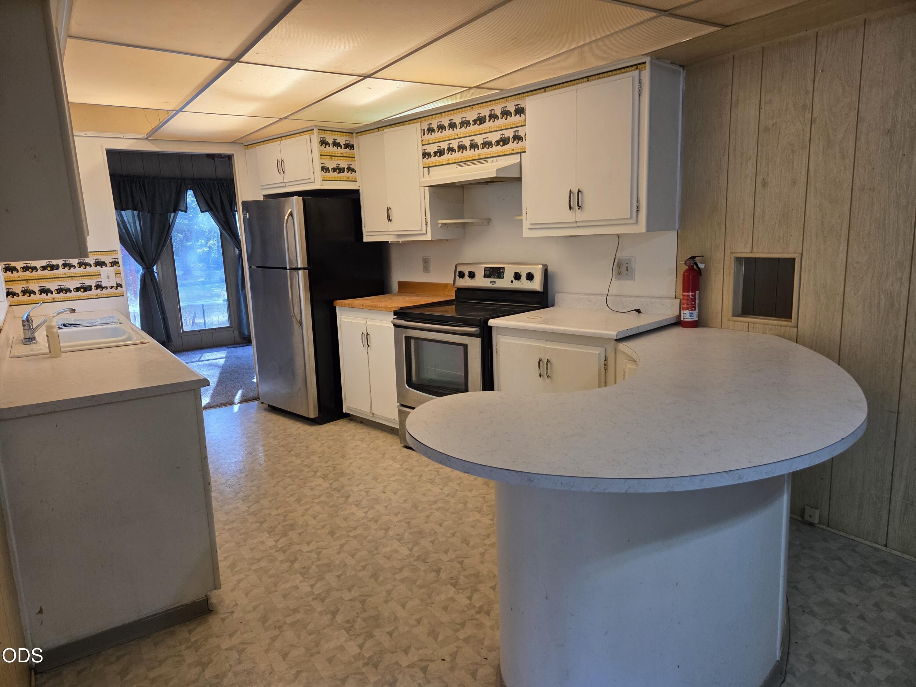 Kitchen with white cabinets, stainless-steel appliances, and a large rounded peninsula.