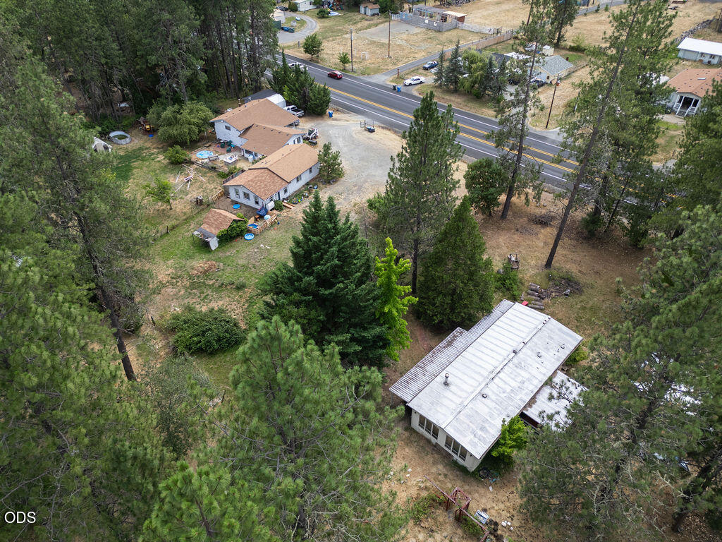 Aerial view of wooded acreage with several homes and a road along the property.