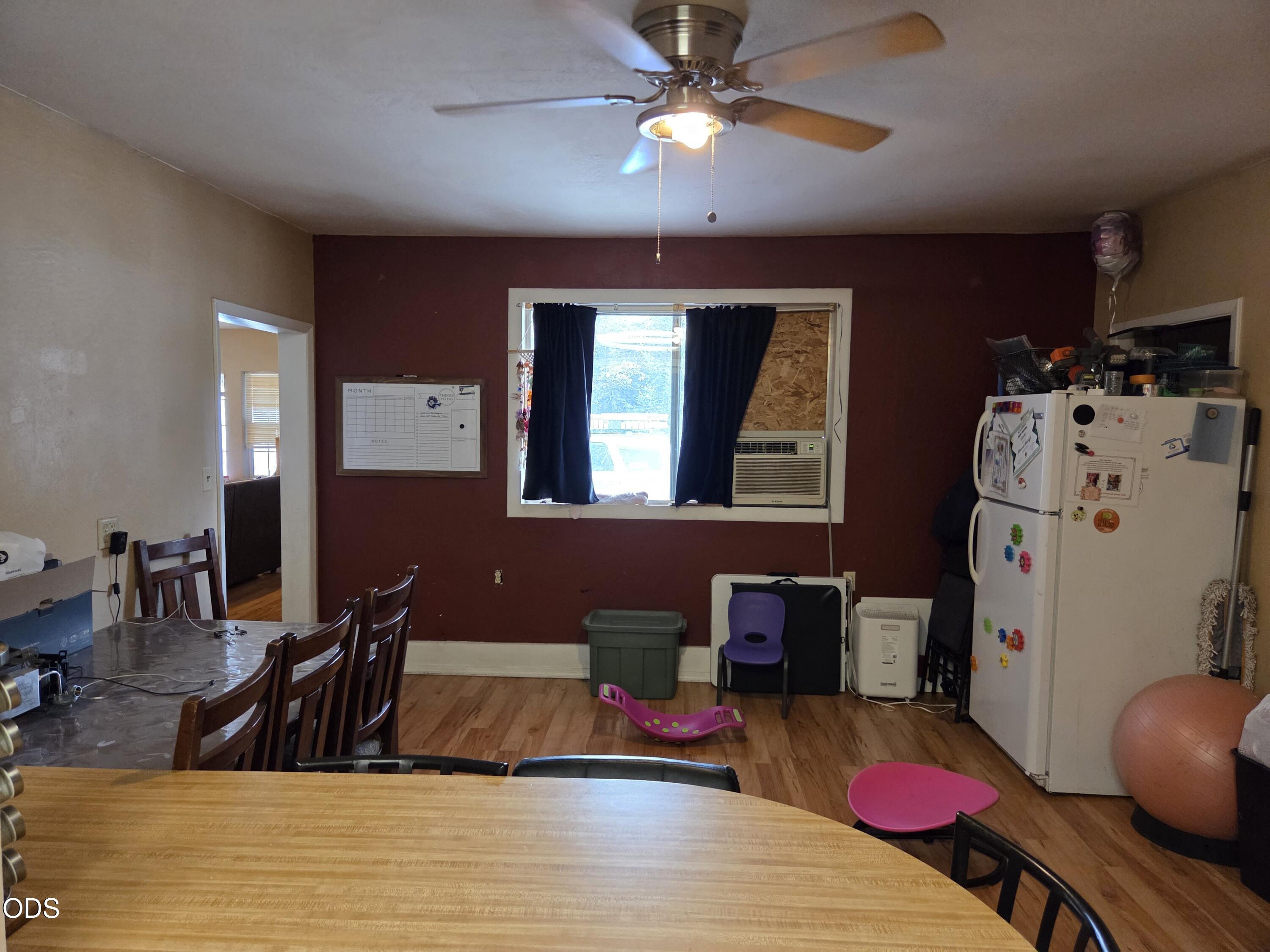 Kitchen and dining area with a large wooden table, crowded refrigerator, and window air conditioner.