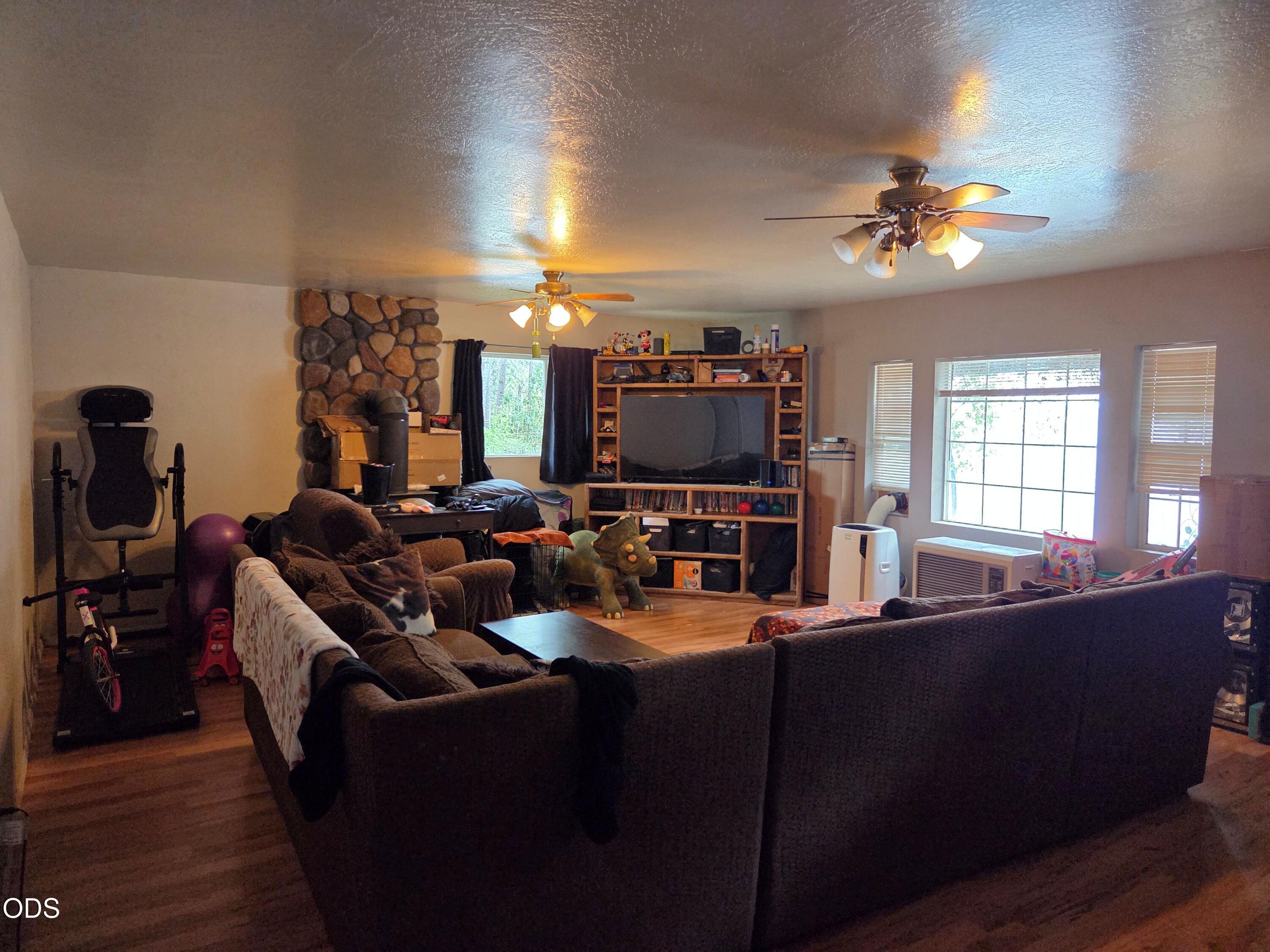 Furnished living room with a stone accent wall, large media shelving, and dark sectional sofas.