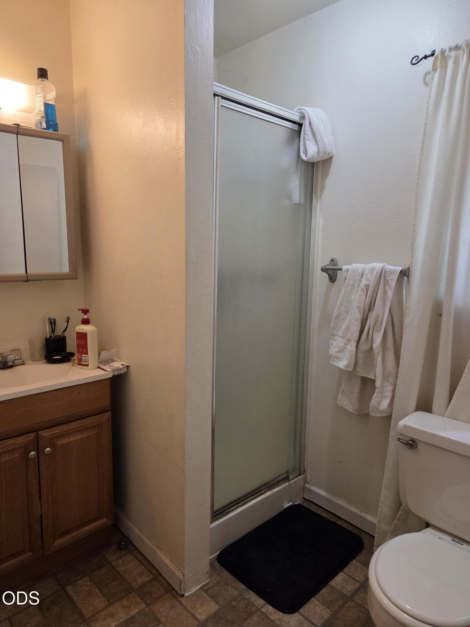 Bathroom with a glass-enclosed shower, wooden vanity, and white towels.