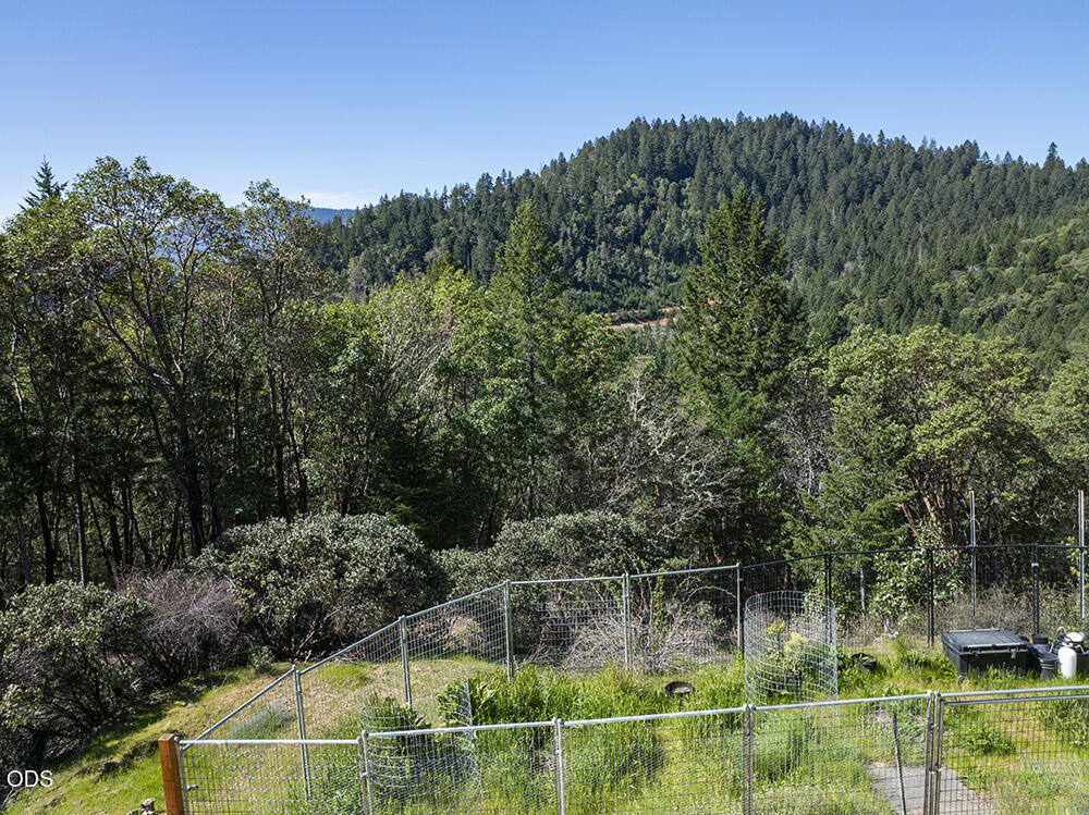 Fenced garden overlooking a forested hillside and wooded ridges.