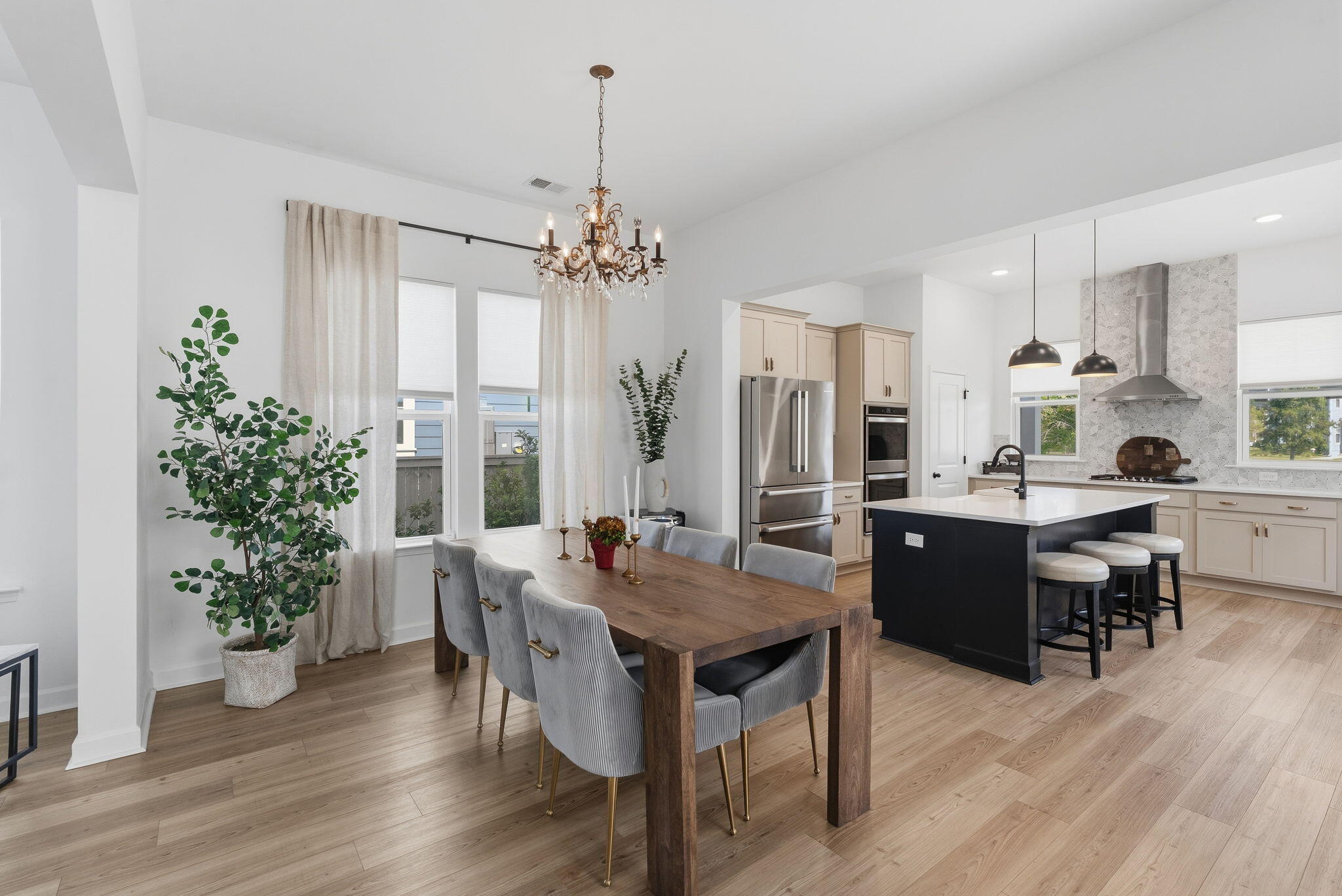 Open-plan dining room and kitchen with a wood table, dark island, and stainless steel appliances.