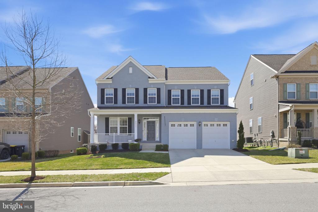 Two-story gray house with dark shutters, a covered porch, and a two-car garage.