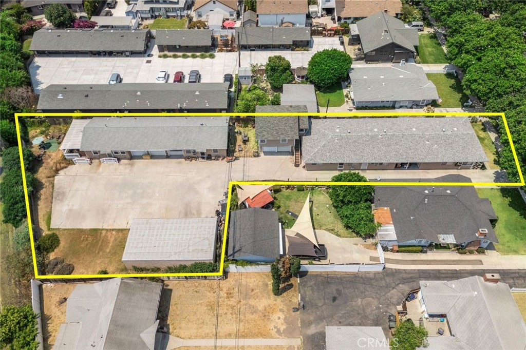Aerial view of a yellow-outlined property with long buildings and a broad paved lot.