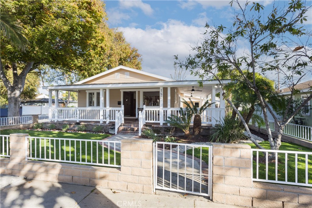 Single-story home with a broad covered porch, white railings, and a gated front yard.