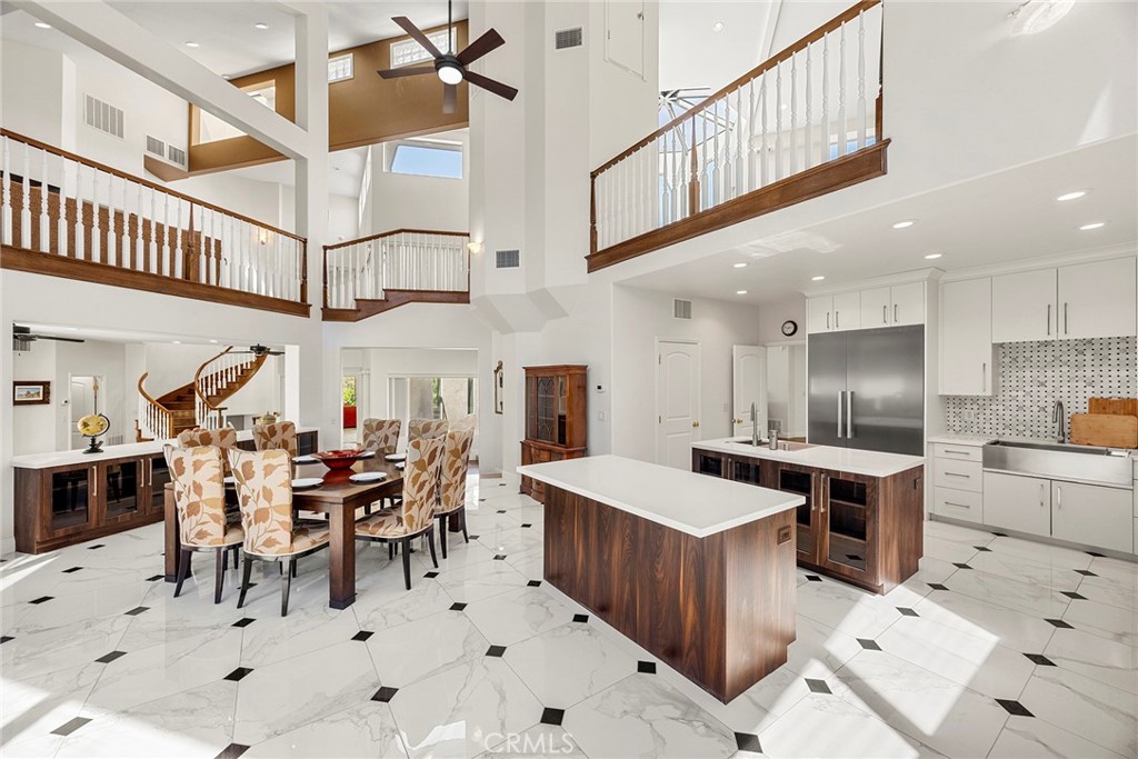Open-plan kitchen and dining room with a large wood-paneled island and upper-level balcony.