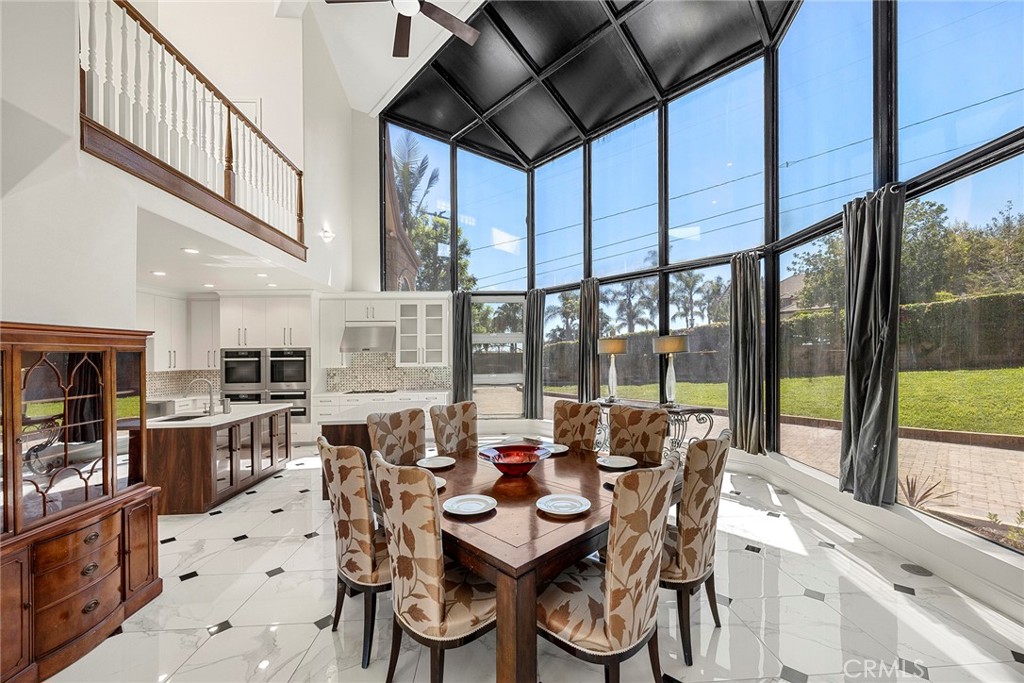Dining room and kitchen with a tall wall of windows overlooking the lawn and patio.