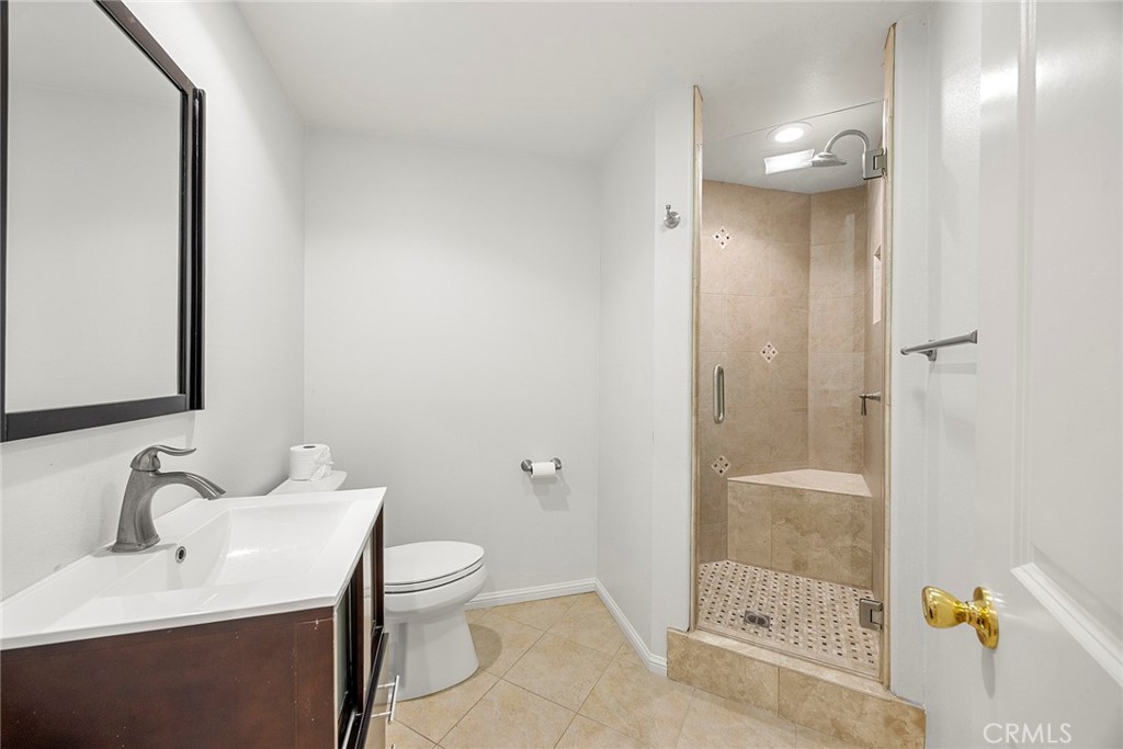 Bathroom with a dark wood vanity and a beige tiled walk-in shower with a built-in bench.