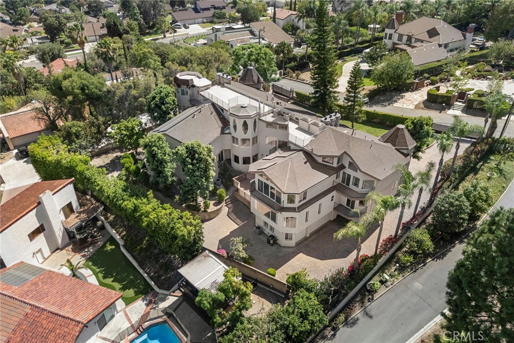 Aerial view of a large stucco home with tower-like roof features and landscaped grounds.