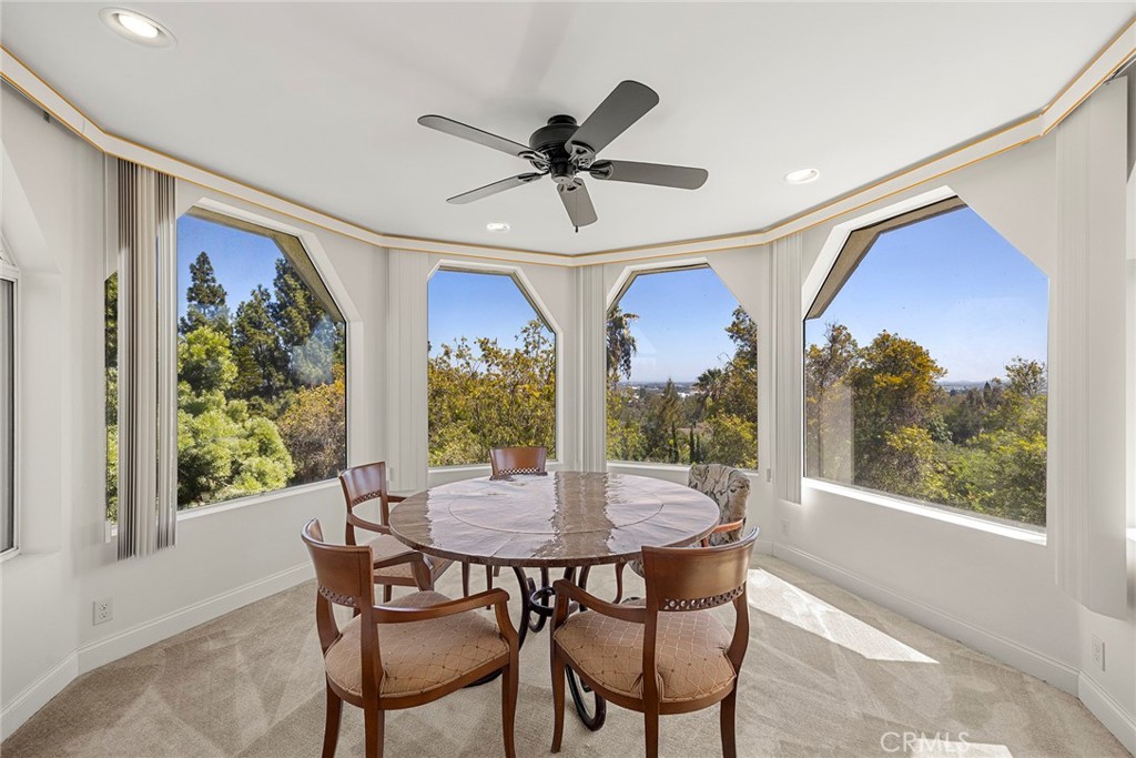 Dining room with a round table and large windows overlooking trees.